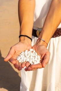 A young woman with stones in her hand on Popcorn Beach near the town of Corralejo