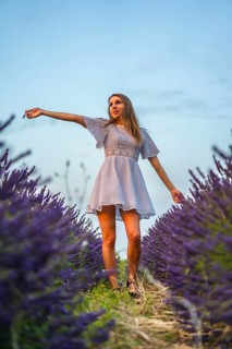 A young blonde Caucasian woman in a white dress in a cultivated lavender field in Navarra