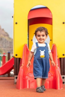 Baby playing in a playground having fun in summer