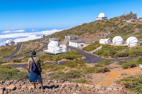 A young man on the trail looking at the telescopes of the Roque de los Muchachos national park on top of the Caldera de Taburiente