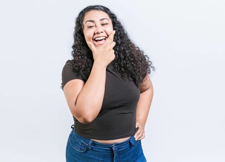 Happy young latin woman holding chin laughing isolated. Portrait of funny latin woman smiling isolated. Portrait of young woman nicaraguan