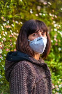 A young woman with a mask on her first walks in mistrust. First walks of the uncontrolled Covid-19 pandemic