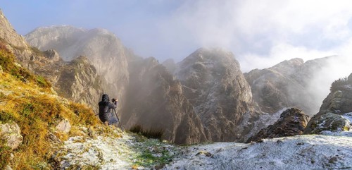Panoramic of a photographer taking a photo with the tripod in the snowy winter sunset