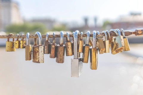 Old rusty padlocks hanging on bridge railing