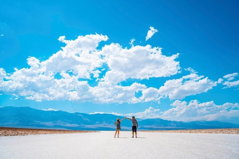 A couple of tourists walking in the white salt flat of Badwater Basin
