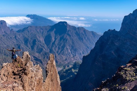 A young man after finishing the trek at the top of the volcano of Caldera de Taburiente near Roque de los Muchachos looking at the incredible landscape