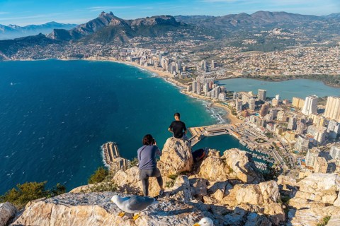 A young man photographed sitting on top of the Penon de Ifach Natural Park in Calpe