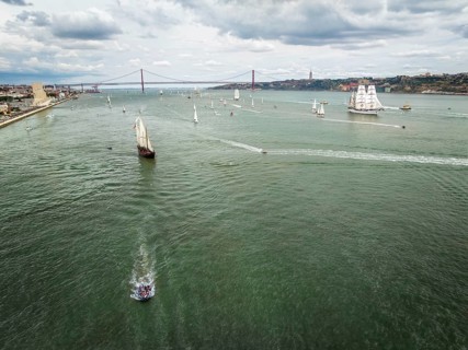 Aerial drone view of tall ships with sails sailing in Tagus river towards the Atlantic ocean in Lisbon