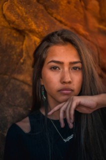 A young pretty brunette Latina with long straight hair in a short black T-shirt and pink pants. Portrait of the girl in a close-up shot