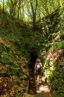 A young woman on her way to a cave on the trail at Levada do Caldeirao Verde