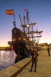 A tourist visiting the old ship at sunset on the promenade of Muelle Uno in the Malagaport of the city of Malaga