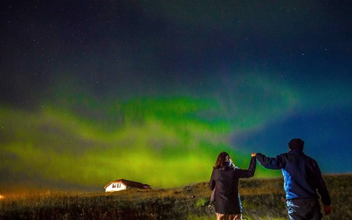 A couple in Northern lights in the sky on the Reykjanes peninsula in southern Iceland
