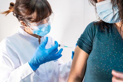 A woman doctor with a face mask applying the coronavirus vaccine