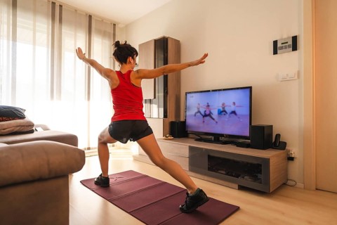 A young woman doing stretching in the room following the instructions of the online teacher. Sport in the covid19 quarantine at home