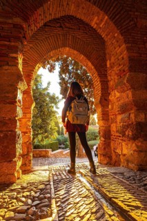 A tourist at sunset at the gate of the Alcazaba wall in the city of Malaga