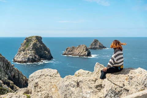 A young tourist girl looking at the sea at Pen Hir Point on the Crozon Peninsula in French Brittany