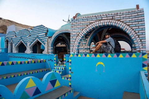 A young tourist sitting on a beautiful terrace of a traditional blue house in a Nubian village along the Nile river and near the city of Aswan. Egypt