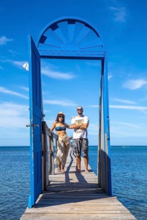 A couple at a blue door on the beach of Sandy Bay on Roatan Island. Honduras