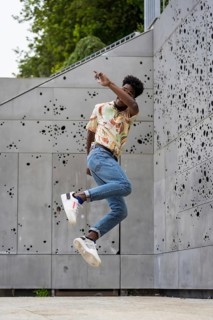 Vertical photo of a african american man jumping high outdoors