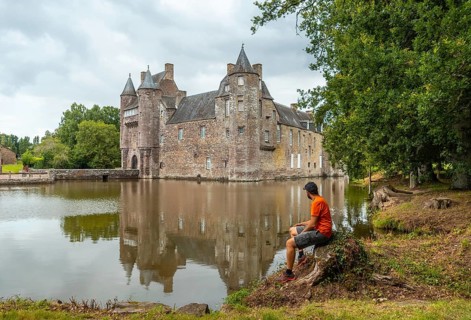 A young man at the lakeside medieval Chateau Trecesson