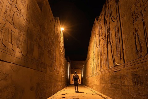 Un joven turista en los pasillos a la noche del templo de Kom Ombo con el traje tradicional