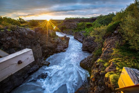 Gorgeous sunset on the wooden bridge of the Barnafoss river