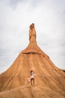 Brunette Caucasian girl with a white dress and a straw hat in the Castildetierra of the Bardenas Reales desert