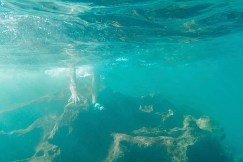 A young Caucasian brunette with flip flops getting into the water
