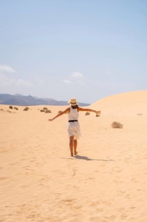 A young tourist wearing a hat walking through the dunes of the Corralejo Natural Park