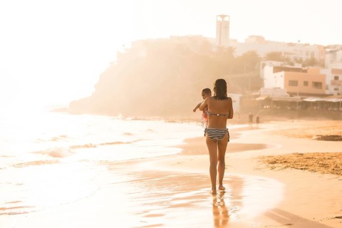 A young mother with her six-month-old baby at sunset on a beach