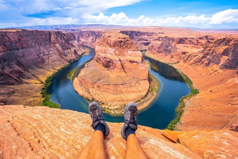 Crossed feet resting watching Horseshoe Bend and the Colorado River in the background