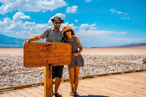 A couple tourists walking white salt of Badwater Basin