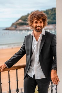 Street style with a young brunette caucasian man in a black suit and a white shirt in a luxurious hotel