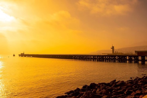 Old loading dock called Cable Frances at orange sunset on the beach of San Miguel in the city of Almeria