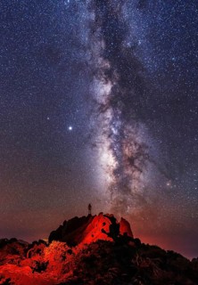 Silhouette of a young man under the stars looking at the lactea way of the Caldera de Taburiente near the Roque de los Muchahos on the island of La Palma