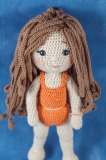 Close-up of a handmade amigurumi doll on a blue background