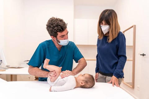 Frontal photo of a young doctor and mother during a baby check up in a clinic