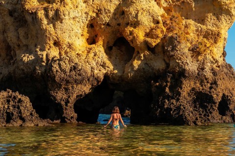 A woman in the water on a bow at Praia dos Arrifes