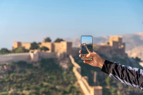A young tourist taking a photo at the viewpoint of Cerro San Cristobal de la Muralla de Jairan and the Alcazaba in the town of Almeria