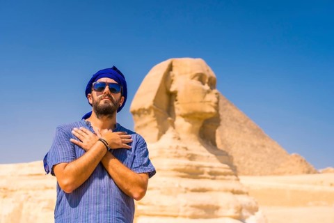 A young tourist near the Great Sphinx of Giza dressed in blue and a blue turban
