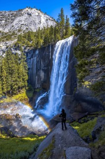 A woman in Long Vernal Falls waterfall in Yosemite National Park. California