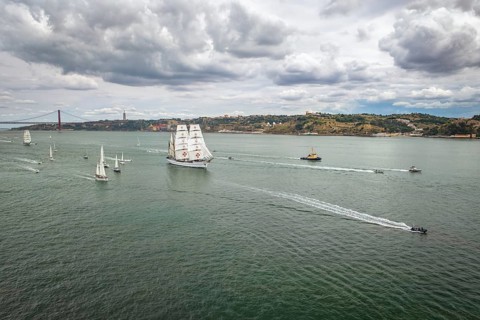 Aerial drone view of tall ships with sails sailing in Tagus river towards the Atlantic ocean in Lisbon