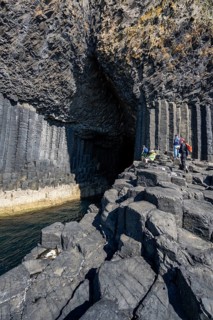Tourists at the entrance to the 80 metre long and 10 metre wide Fingal's Cave on the uninhabited rocky island of Staffa
