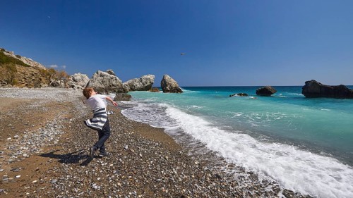 Boy hurls a stone in the air towards the sea