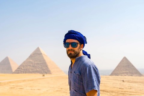 A young tourist wearing blue turban and sunglasses enjoying the Pyramids of Giza