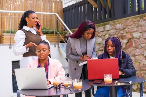 Young businesswomen of black ethnicity. At a business meeting in a cafeteria with computers and coffee on the table. Teamwork