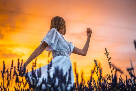 A young blonde Caucasian woman in a white dress in a cultivated lavender field in Navarra