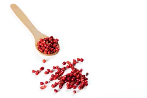 Wooden spoon with pink peppercorns isolated on white background and copy space