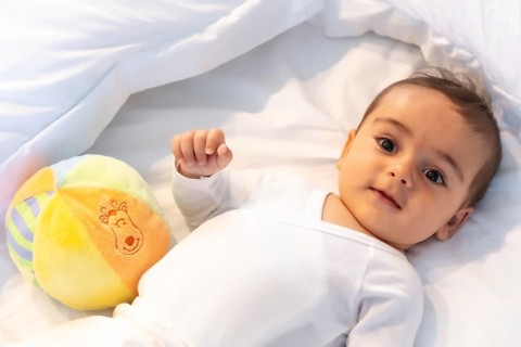 5 month old Caucasian baby smiling in white bed just woken up