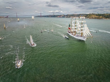 Aerial drone view of tall ships with sails sailing in Tagus river towards the Atlantic ocean in Lisbon